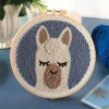 Alpaca wall art punch needle kit showing cute white alpaca design in embroidery hoop with yarn and crafting tools