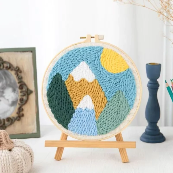 Punch needle embroidery kit showing pastel mountain design in hoop frame with yarn and tools for beginners