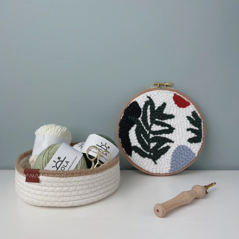 Punch needle embroidery kit with wild leaves design, organized yarn supplies in woven basket, and wooden punch needle tool