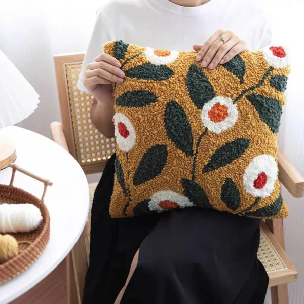Handcrafted needle punch pillow with colorful floral pattern on wooden chair, showing textured rose design perfect for home decor