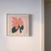 DIY flower embroidery wall art framed and hung, featuring soft pink petals and green leaves