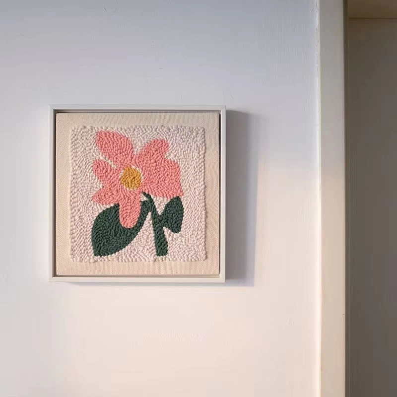 DIY flower embroidery wall art framed and hung, featuring soft pink petals and green leaves