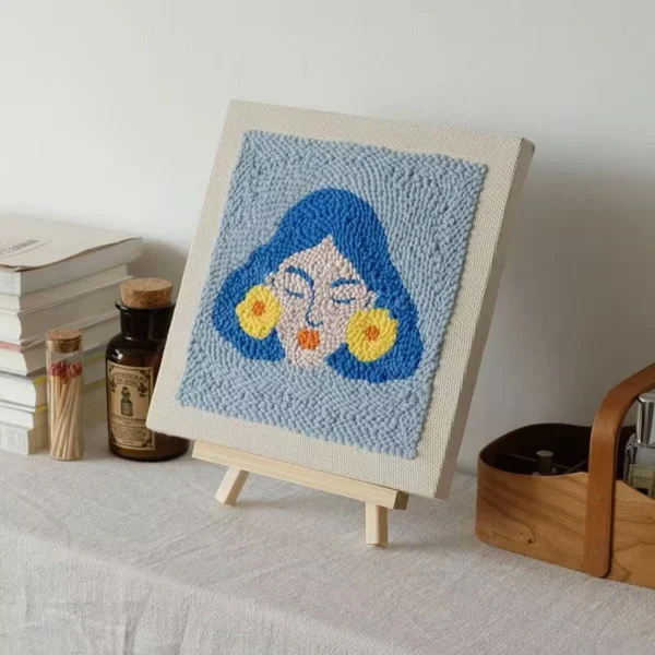 Frida Kahlo wall art punch needle piece on easel showing blue-haired portrait with yellow flower earrings
