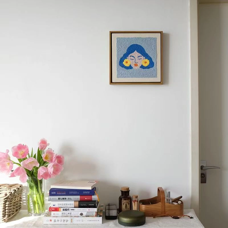 Framed Frida Kahlo wall art with blue hair and yellow flowers hanging above desk with pink tulips and books
