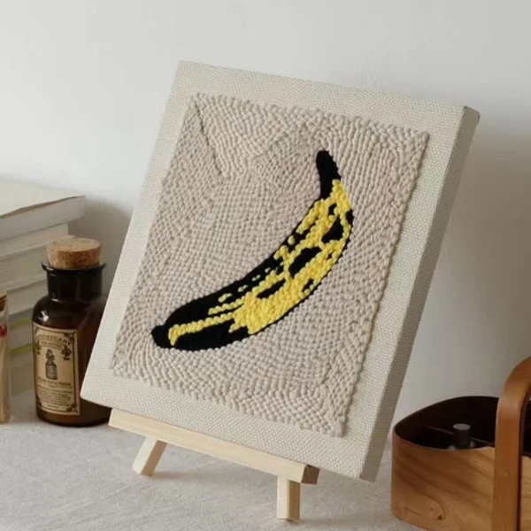 Andy Warhol inspired yellow banana punch needle art on beige canvas displayed on wooden easel, pop art home decor
