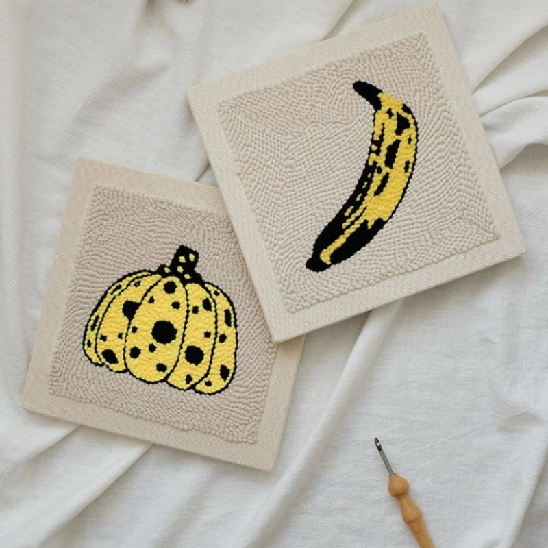 Two punch needle canvases featuring Andy Warhol banana and Yayoi Kusama pumpkin designs, artist series craft collection