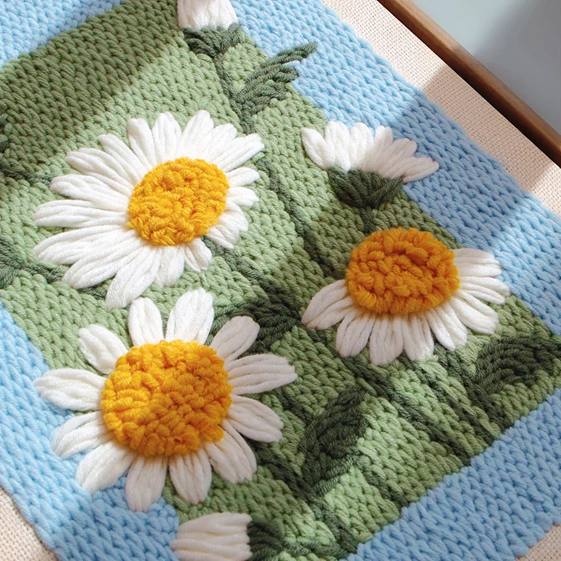 Close-up of punch needle daisy wall art in sunlight, showing vibrant texture and handmade detail.