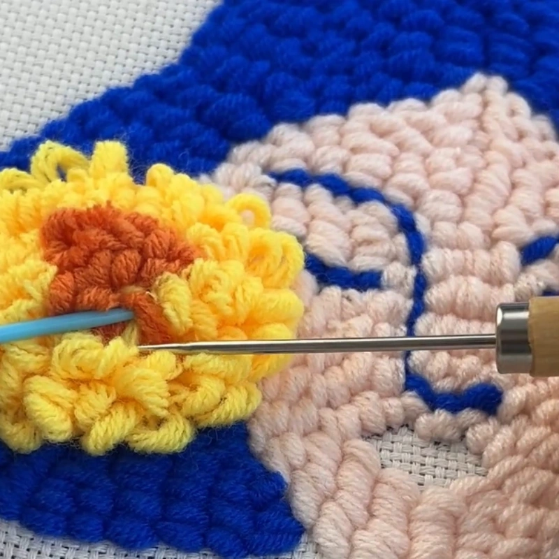 Picking yarn loops to shape a 3D flower design in punch needle work.