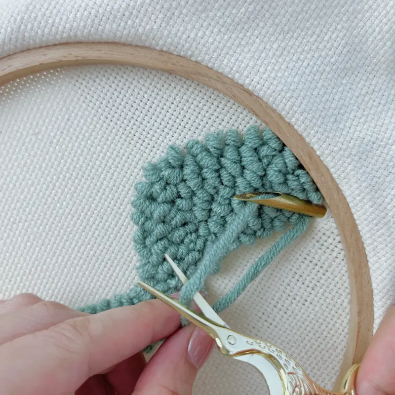 Finishing green block – punch needle tip still in fabric, pull 3–5 cm yarn from back and trim