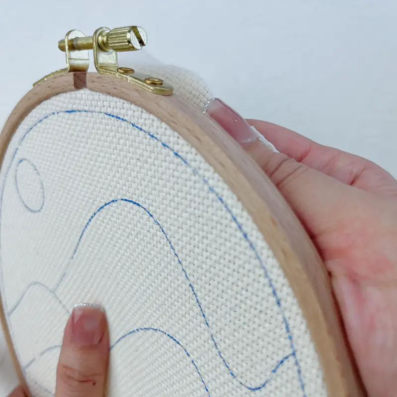 Adjusting fabric tension to ensure even tightness across the hoop.